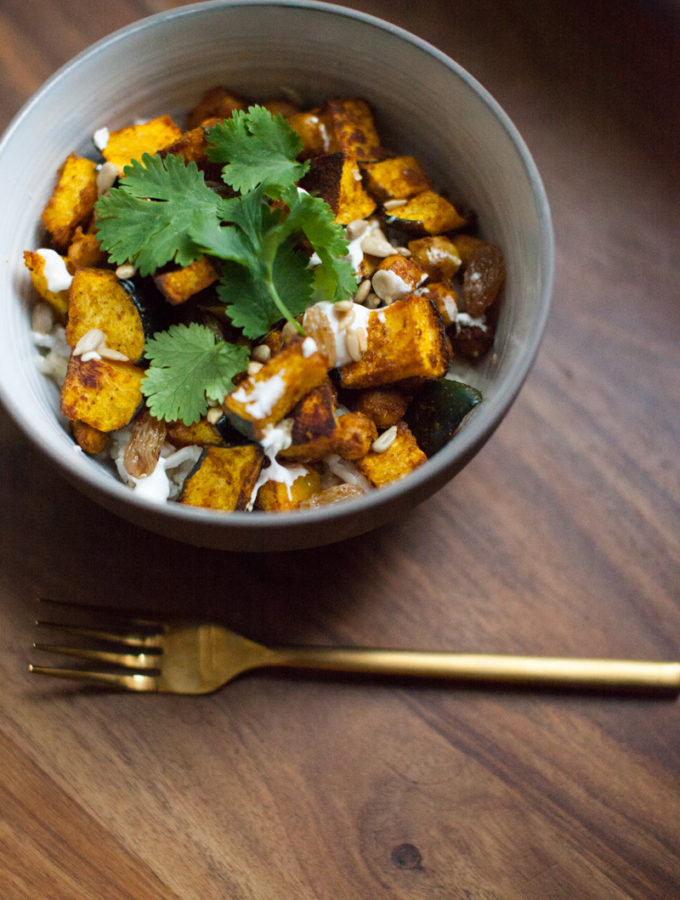 An easy weeknight vegetarian dinner or warm lunch recipe for a spicy curry roasted squash bowl with lemon yogurt and pickled golden raisins.