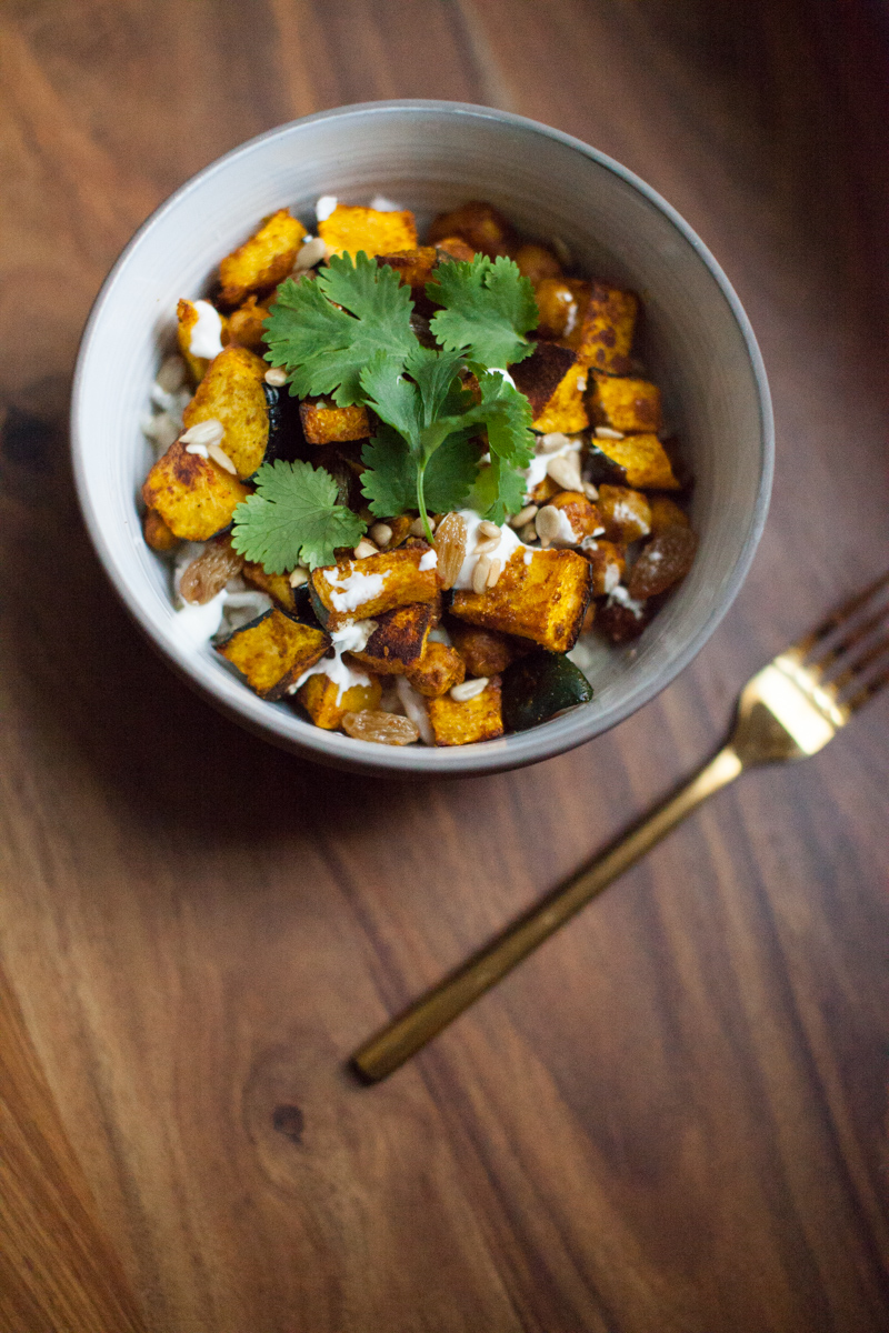 An easy weeknight vegetarian dinner or warm lunch recipe for a spicy curry roasted squash bowl with lemon yogurt and pickled golden raisins. 